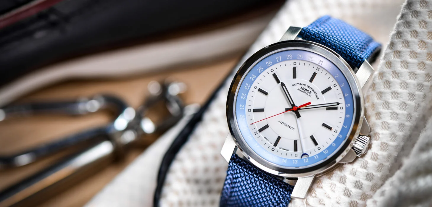 Armbanduhr "29er Zeigerdatum" mit blauem Canvasband steht vor hellem Stoff.