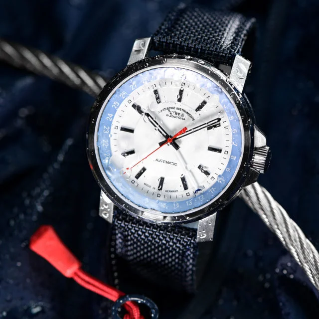 Armbanduhr "29er Zeigerdatum" am blauen Canvasband steht auf dunklem Untergrund mit hellem Seil.